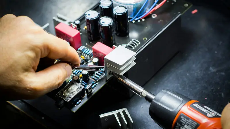 Mano che lavora su una scheda elettronica con un cacciavite